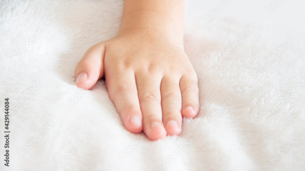 Closeup of left hand of a little girl placed on a white soft and cozy blanket Closeup of left hand of a little girl placed on a white soft and cozy blanket