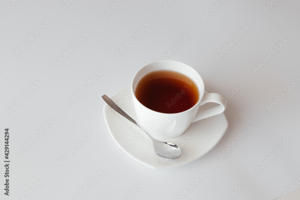 One white cup of tea with saucer and spoon on white background. Top view of coffee mug. Nice banner for cafe menu or restaurant. Morning breakfast. Start the day with coffee One white cup of tea with saucer and spoon on white background. Top view of coffee mug. Nice banner for cafe menu or restaurant. Morning breakfast. Start the day with coffee