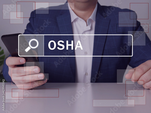 Occupational Safety and Health Administration OSHA phrase on the screen. Businessman use cell technologies at office. Concept search and Occupational Safety and Health Administration OSHA .