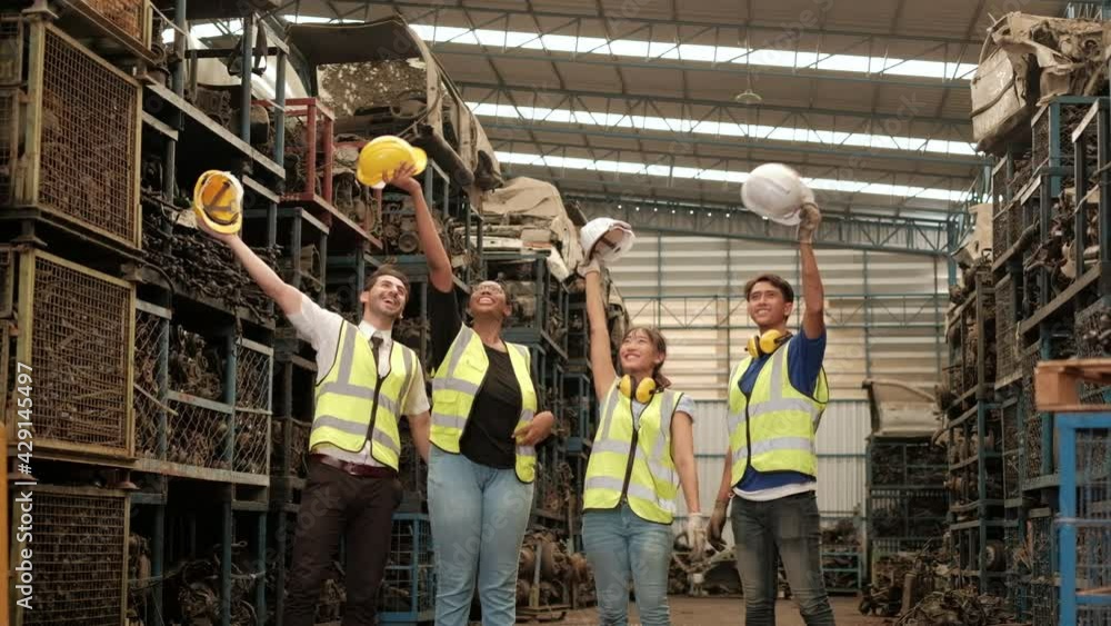 Workers of various races in factory safety uniforms are expressing their joy. By removing helmets and waving them in warehouses of spare parts, engines, and machinery in automotive industry. Workers of various races in factory safety uniforms are expressing their joy. By removing helmets and waving them in warehouses of spare parts, engines, and machinery in automotive industry.