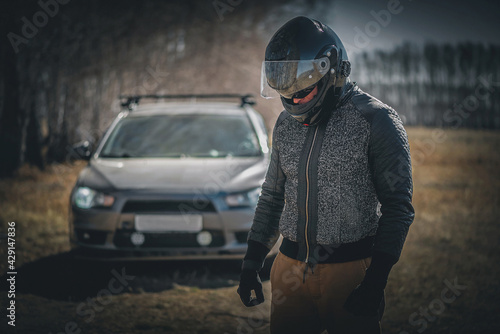 Sad rally driver with his head down is standing on the road. Lose the race concept. © Dmitriy
