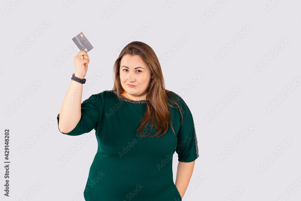 Very proud smug businesswoman wearing green dress showing credit card over grey background. Confident banker, plus size woman showing your sale promotion. Very proud smug businesswoman wearing green dress showing credit card over grey background. Confident banker, plus size woman showing your sale promotion.