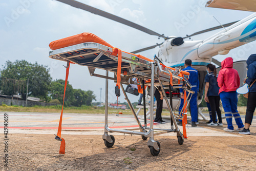 A stretcher is parked in front of a helicopter to transport a sick person.