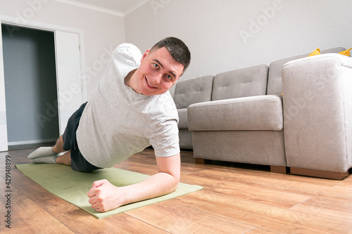 Strong Athletic Fit Man in T-shirt and Shorts is Doing Exercises at Home.