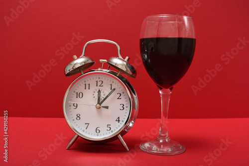 glass of red wine next to an alarm clock 