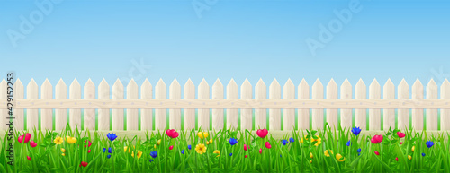 Wooden picket fence, flowers and green grass on background of blue sky. Vector realistic landscape with barrier with wood texture and summer meadow plants. Backyard, garden or lawn with enclosure