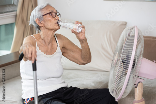 Fotografie Thirsty elderly woman drinking water to quench thirst,refresh in hot summer weat