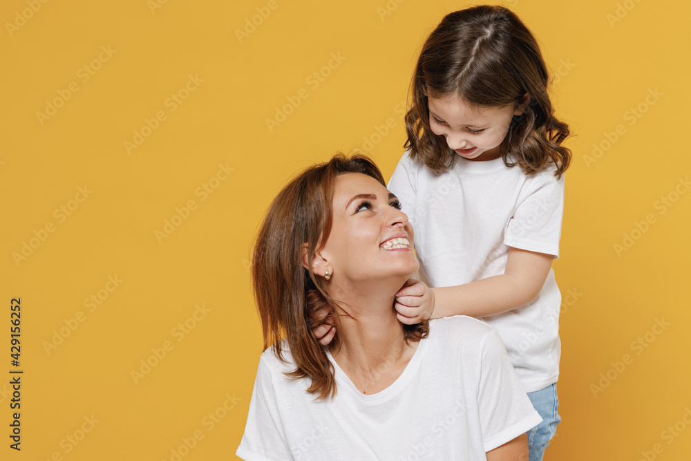 Happy woman in basic white t-shirt have fun with cute child baby girl 5-6 years old hugging. Mom little kid daughter isolated on yellow orange color background studio Mother's Day love family concept Happy woman in basic white t-shirt have fun with cute child baby girl 5-6 years old hugging. Mom little kid daughter isolated on yellow orange color background studio Mother's Day love family concept