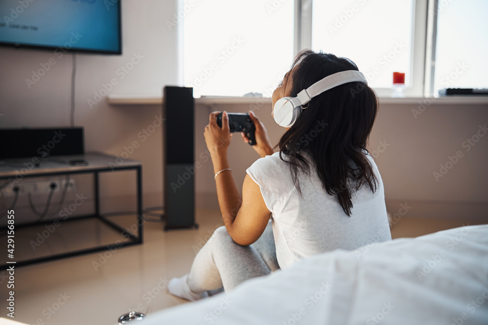 Young woman in headphones playing video game at home Young woman in headphones playing video game at home