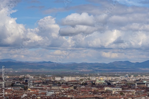 Aerial view of urban landscape with many administrative and residential buildings and grey clouds on blue sky background. Sofia, the capital city of Bulgaria, East Europe. Panoramic natural sight.