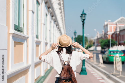 Photography Behind of young asian woman with backpack and straw hat travel in old town Bangk