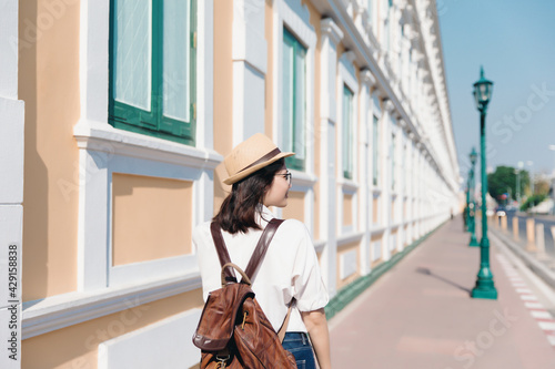 Canvas Print Behind of young asian woman with backpack and straw hat travel in old town Bangk