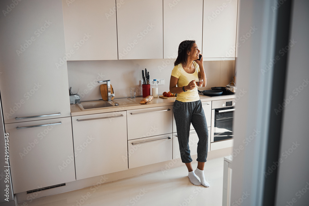 Cheerful young woman talking on mobile phone at home Cheerful young woman talking on mobile phone at home