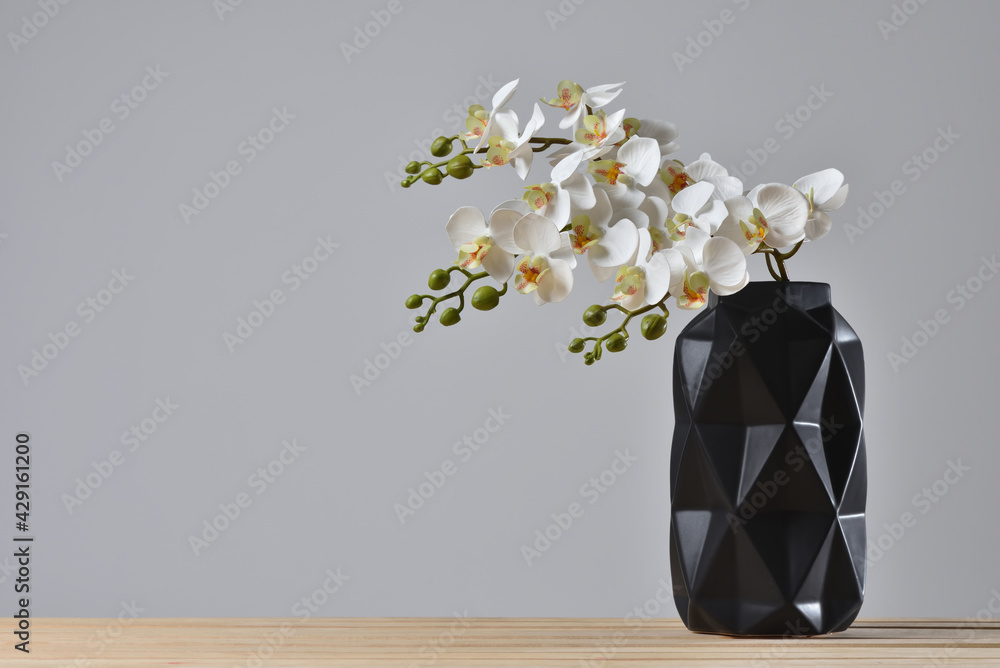 Modern black vase with orchid flower on gray background. - obrazy, fototapety, plakaty 