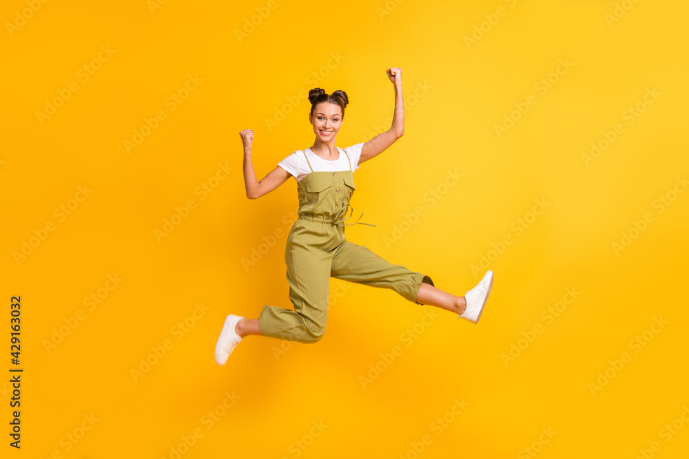 Full length body size view of attractive cheerful girl jumping rejoicing having fun isolated over bright yellow color background