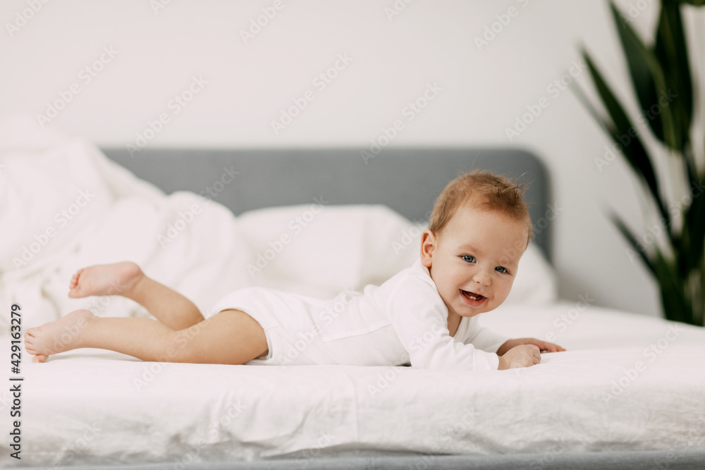 The newborn lies in a snow-white bed under the covers, laughs and indulges The newborn lies in a snow-white bed under the covers, laughs and indulges