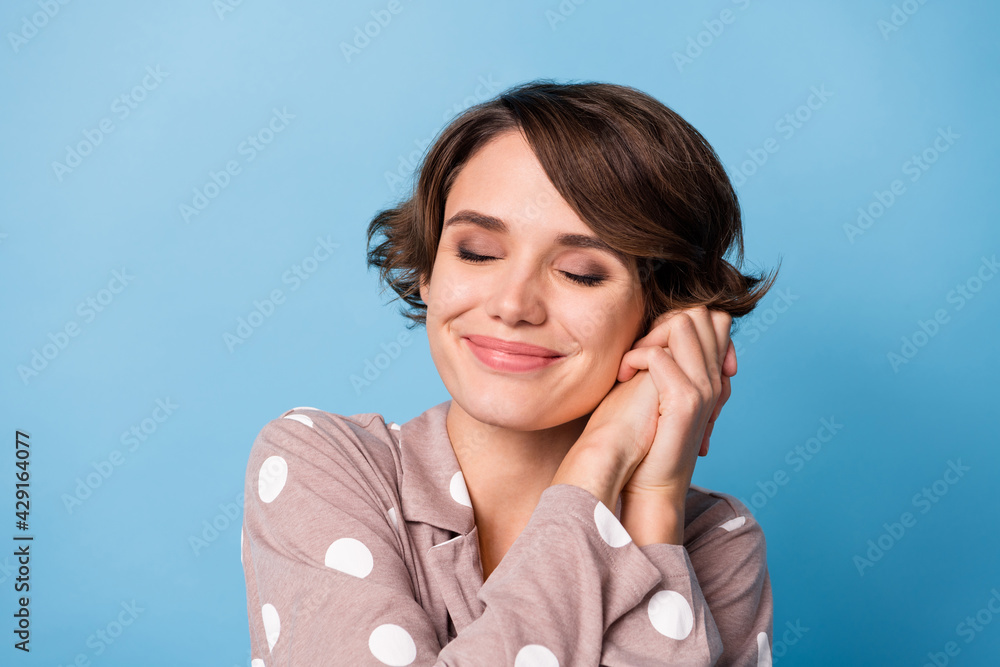 Photo of young adorable girl happy positive smile dream dreamy hands touch cheek isolated over blue color background Photo of young adorable girl happy positive smile dream dreamy hands touch cheek isolated over blue color background