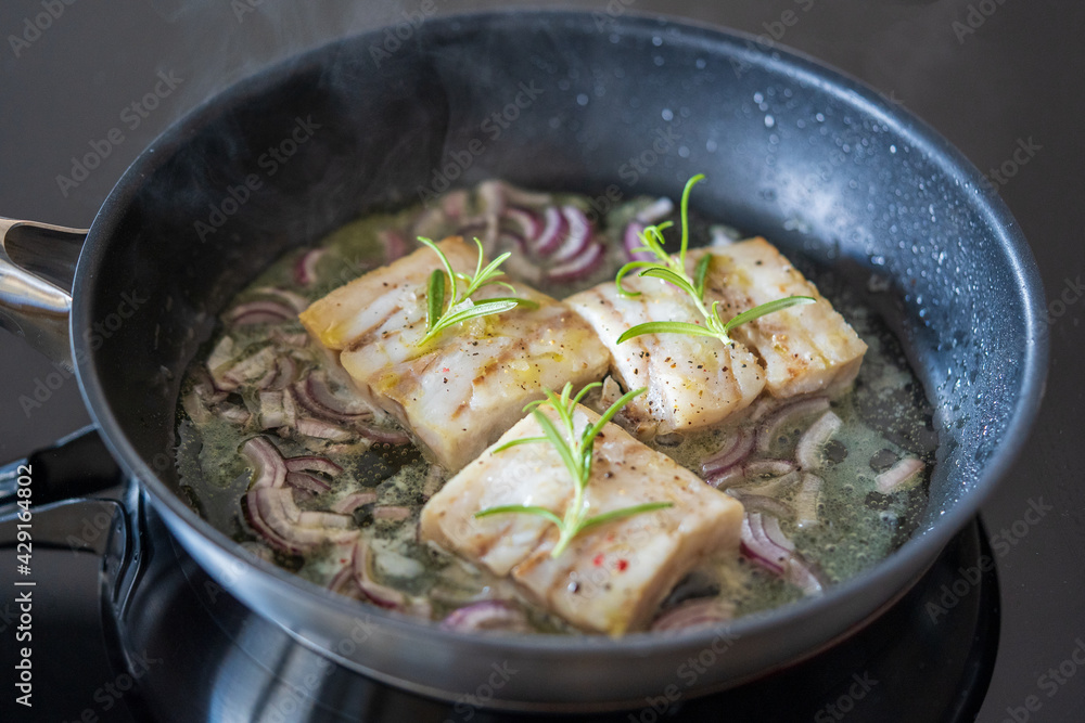 fresh cooking at home - roasted trout fillet in olive oil with red onions and rosemary