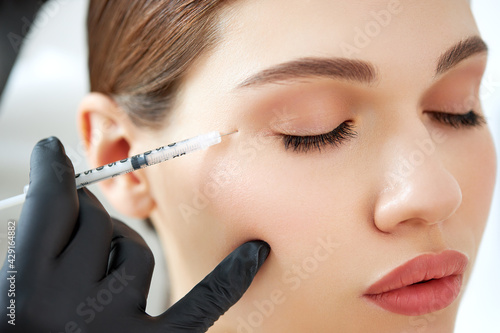 Cosmetician applying lifting injection to female face