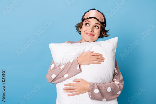 Photo of young attractive girl happy positive smile hug pillow bedtime dream look empty space isolated over blue color background