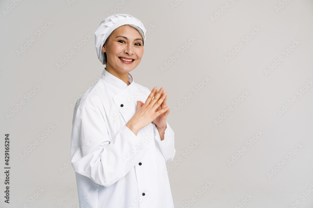 Asian mature woman in white chef uniform smiling at camera Asian mature woman in white chef uniform smiling at camera
