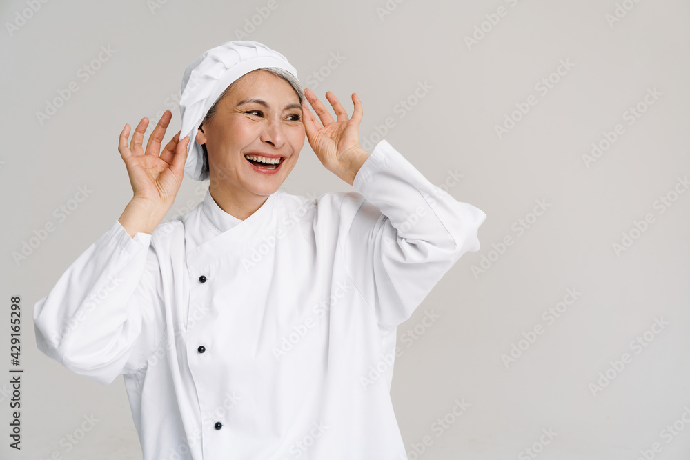 Asian mature woman in white chef uniform smiling and posing at camera Asian mature woman in white chef uniform smiling and posing at camera