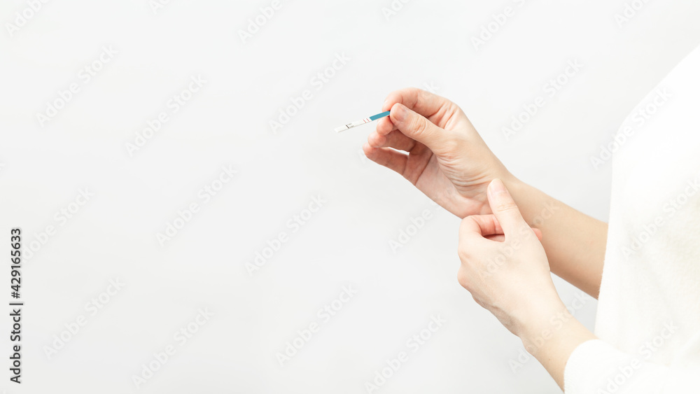 Closeup woman hand holding positive pregnancy test, Two stripes on test. health care concept, selective focus. White background. copy space Closeup woman hand holding positive pregnancy test, Two stripes on test. health care concept, selective focus. White background. copy space