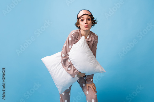 Photo of amazed young girl hold pillow pouted lips wear sleepwear pajama isolated on pastel blue color background