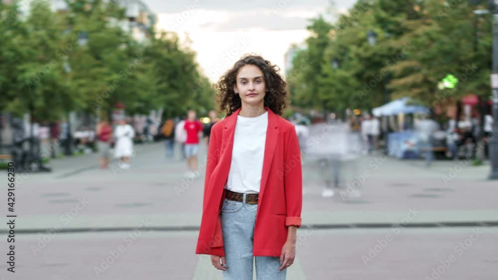 Time lapse portrait of beautiful lady standing in urban street and looking at camera while people are rushing around. Society and modern lifestyle concept. Time lapse portrait of beautiful lady standing in urban street and looking at camera while people are rushing around. Society and modern lifestyle concept.