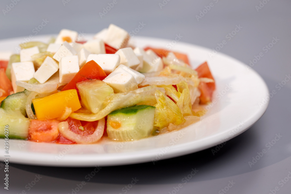Greek salad in a white plate on a gray background Greek salad in a white plate on a gray background