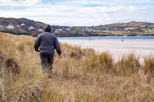 Man walking in the dunes at Portnoo, Narin, beach in County Donegal, Ireland.