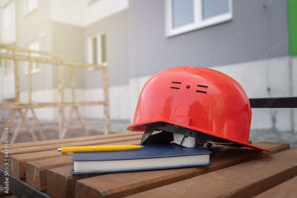 protective helmet and notebook on the background of the construction site protective helmet and notebook on the background of the construction site