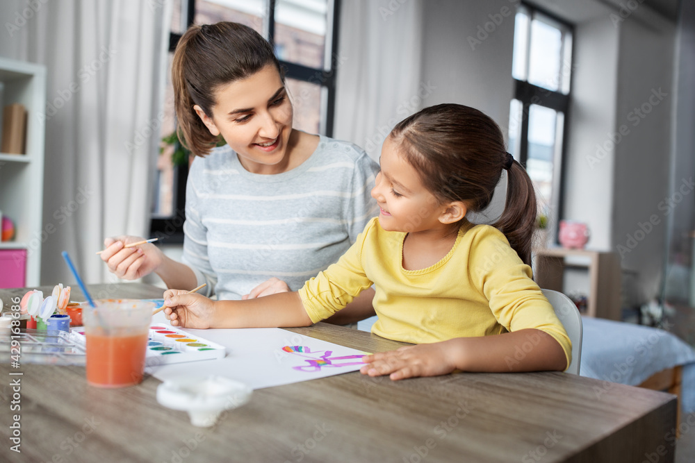 family, motherhood and leisure concept - mother spending time with her little daughter drawing with colors at home family, motherhood and leisure concept - mother spending time with her little daughter drawing with colors at home
