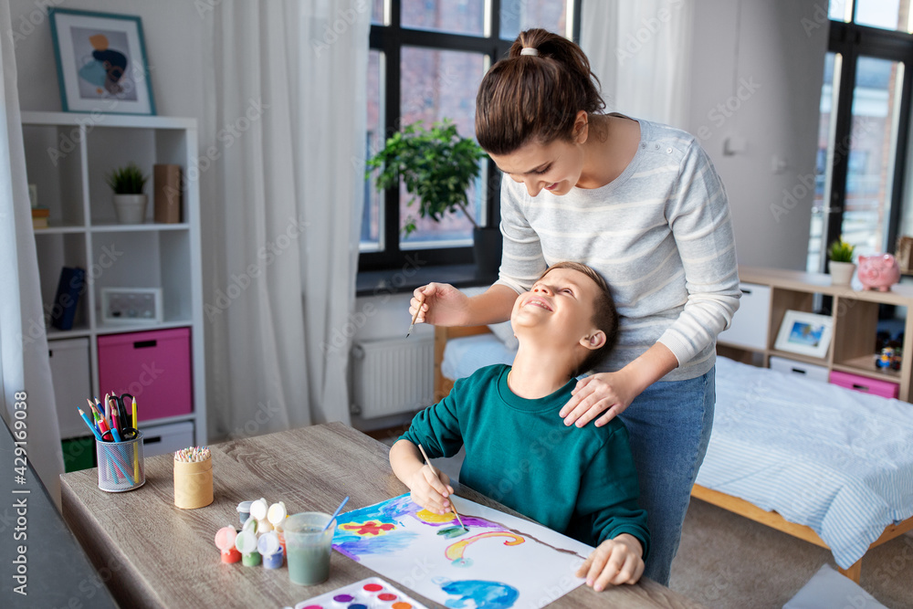 family, leisure and people concept - mother and little son with colors and paper drawing at home family, leisure and people concept - mother and little son with colors and paper drawing at home