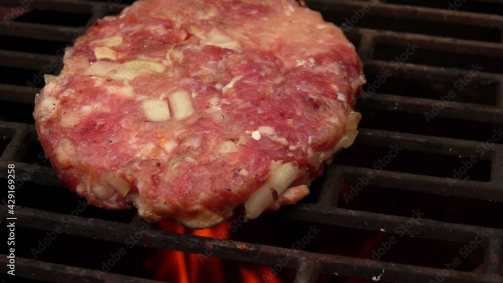 Close-up of the raw meat burger cutlet on the grill grid above the open fire outdoors Close-up of the raw meat burger cutlet on the grill grid above the open fire outdoors