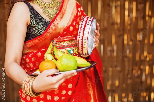 Closeup of hands of Indian woman in a saree, holding plate with fruits for her Karva Chauth prayers photo
