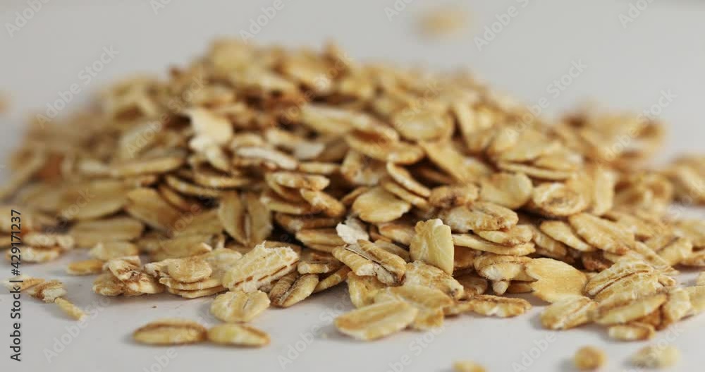 Close up shot of falling rolled oats on a white background spinning on a table. High quality 4k footage Close up shot of falling rolled oats on a white background spinning on a table. High quality 4k footage