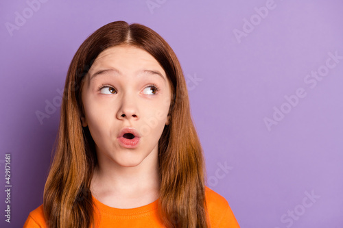 Photo of impressed nice foxy hair girl look empty space wear orange t-shirt isolated on purple color background