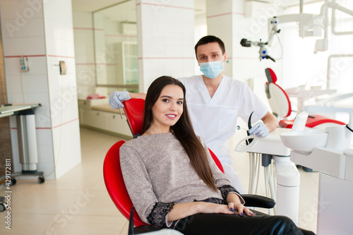 ortrait of the young woman patient examining by male dentist with tools in dental clinic.