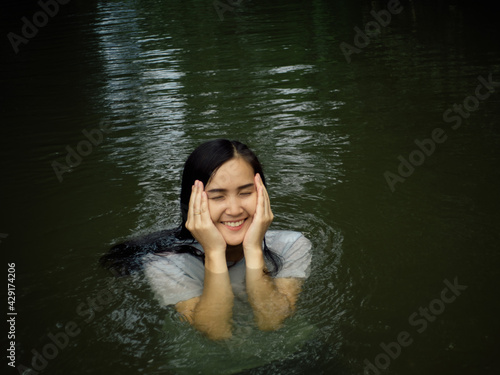 Beautiful woman wearing a white blouse A smiling face happily playing in the stream having fun on holiday. © sukan
