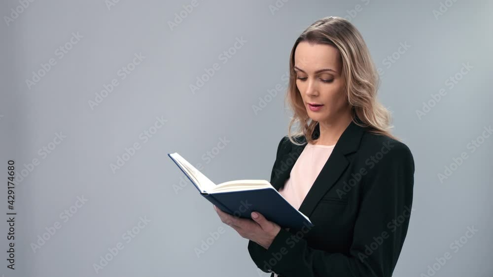 Pensive blonde business woman in suit writing notes isolated on gray. Shot with RED camera in 4K Pensive blonde business woman in suit writing notes isolated on gray. Shot with RED camera in 4K