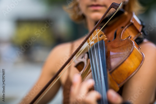 Detail of unrecognizable red-haired violinist playing the violin in the street