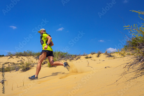 Athlete running off-road in the wild. A man in shorts and a T-shirt is running through the sandy wilderness photo