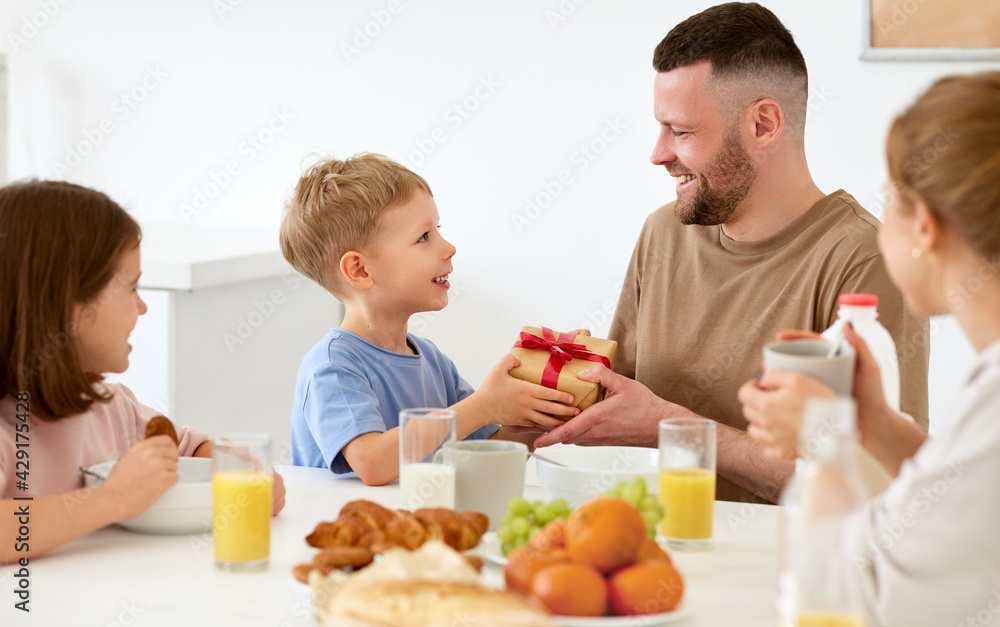 Happy family celebrating Fathers day together while having breakfast in kitchen at home