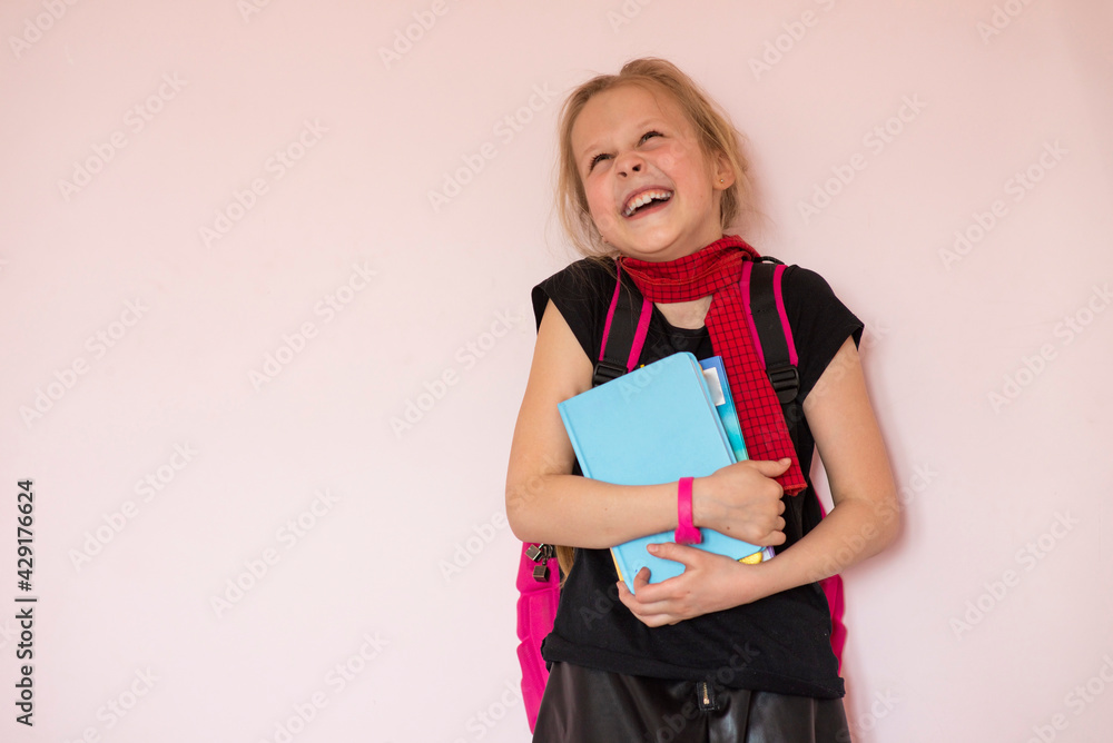 Portrait of a cheerful schoolgirl with a backpack and stationery on a light background. Space for the text. Back to school. Preparing for school. Selective focus Portrait of a cheerful schoolgirl with a backpack and stationery on a light background. Space for the text. Back to school. Preparing for school. Selective focus