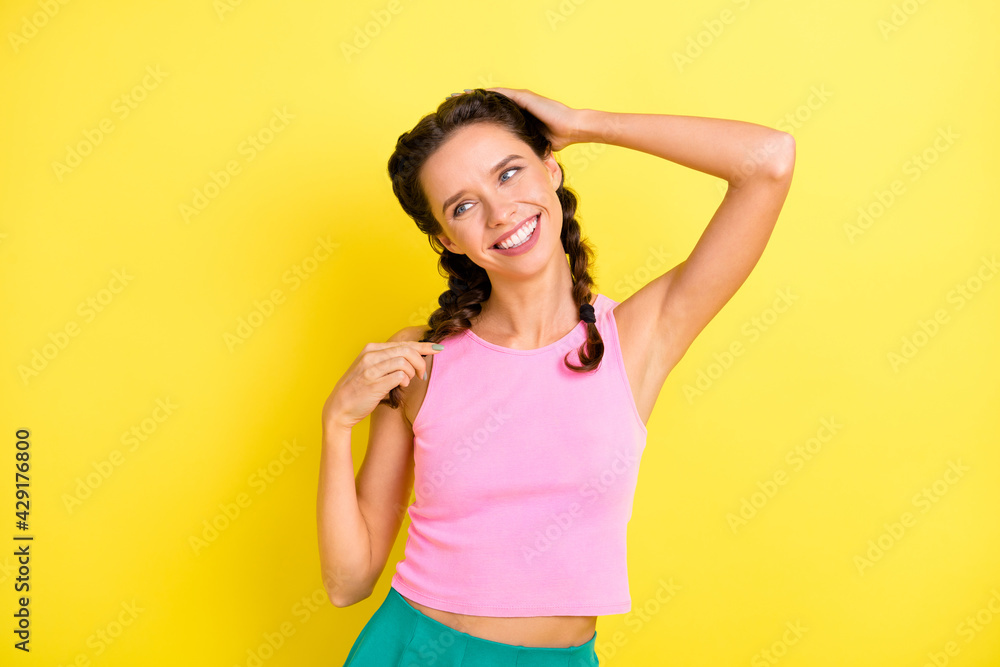 Photo of cute happy young woman look empty space summer mood touch hair braids isolated on bright yellow color background Photo of cute happy young woman look empty space summer mood touch hair braids isolated on bright yellow color background