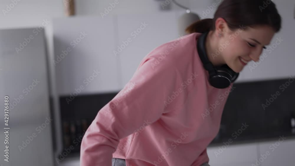 Smiling girl having fun time at kitchen, falling on sofa Smiling girl having fun time at kitchen, falling on sofa