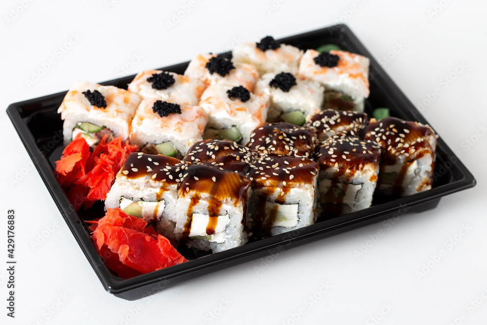 Delivery of Asian food in a plastic container. Rice rolls with shrimp meat, eel and creamy white cheese garnished with sauces Delivery of Asian food in a plastic container. Rice rolls with shrimp meat, eel and creamy white cheese garnished with sauces