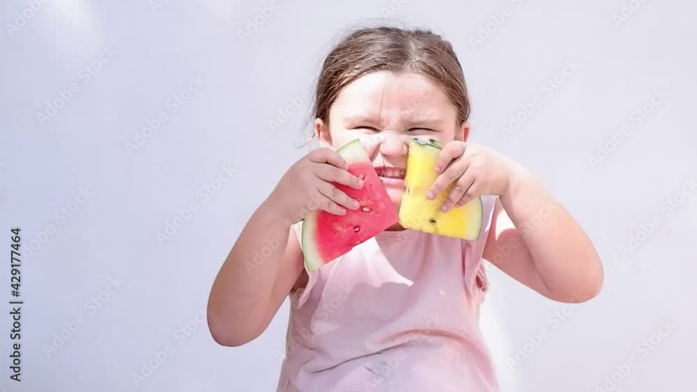 The child is holding pieces of watermelon. The girl smiles and makes a choice between yellow and red watermelon The child is holding pieces of watermelon. The girl smiles and makes a choice between yellow and red watermelon