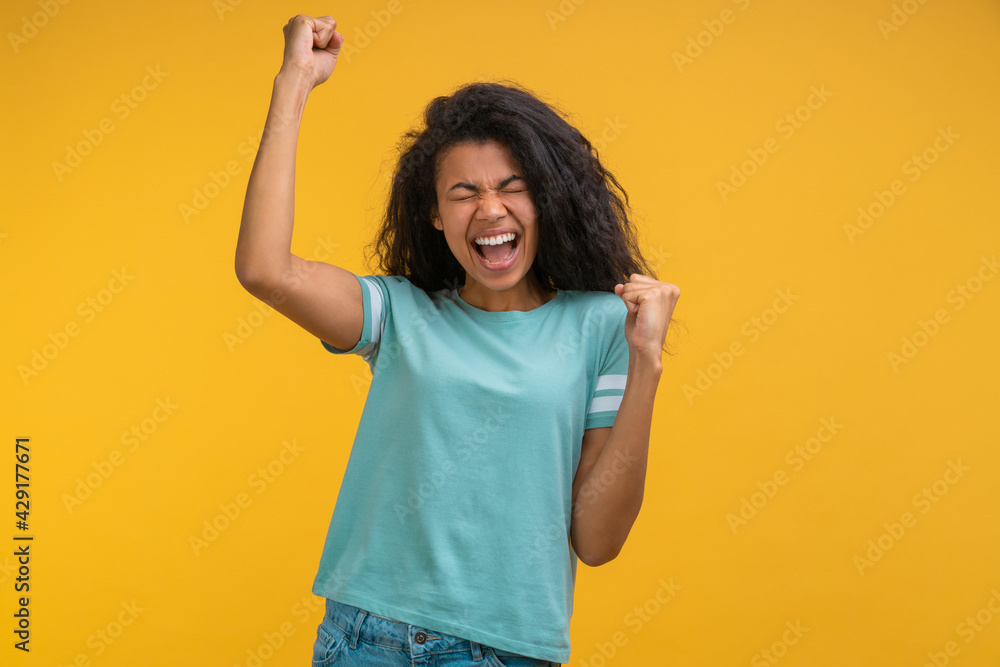 Studio shot of young happy dark skinned woman isolated on bright colored orange yellow background Studio shot of young happy dark skinned woman isolated on bright colored orange yellow background